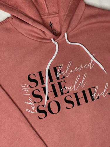Mauve colored hoodie with black and white lettering that says She believed she could so she did